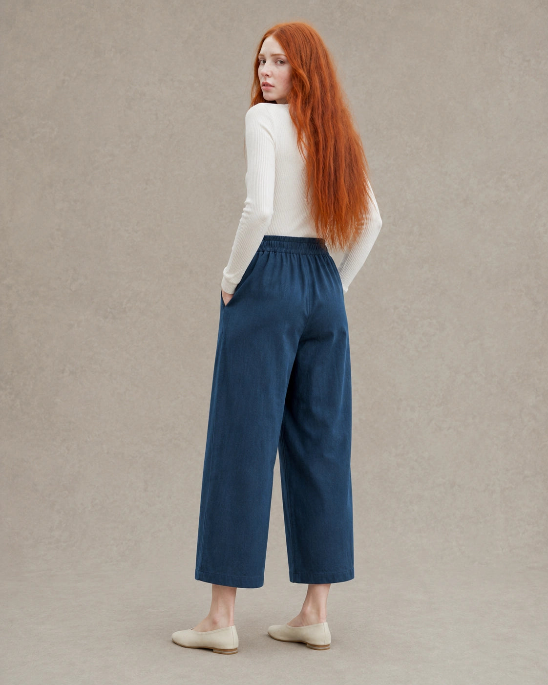 Achteraanzicht van model in een donkerblauwe ingekorte wijde broek dames in tencel-linnenmix met elastische taille.