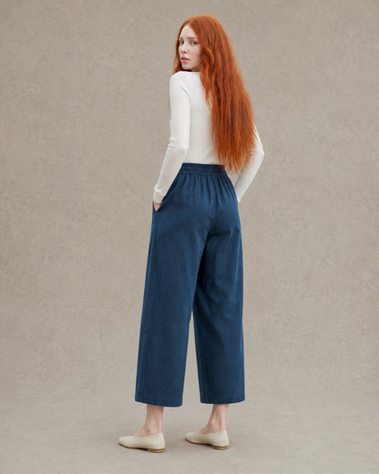 Achteraanzicht van model in een donkerblauwe ingekorte wijde broek dames in tencel-linnenmix met elastische taille.