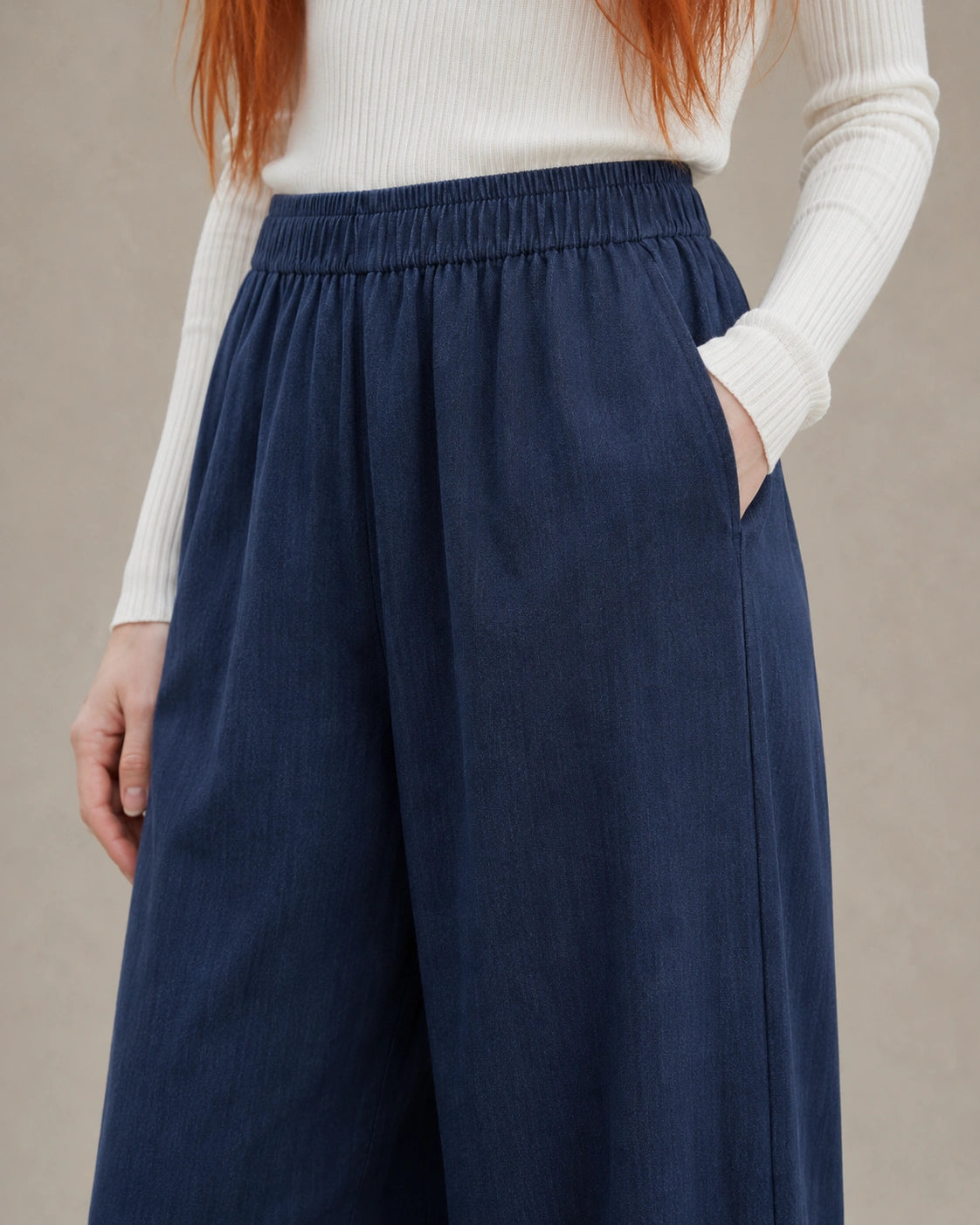 Close-up van de elastische taille en zijzak van een donkerblauwe ingekorte wijde broek dames in tencel-linnenmix.