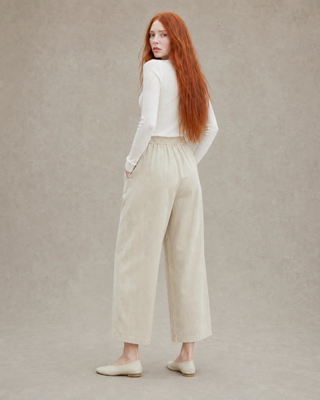 Achteraanzicht van model in een gebroken witte ingekorte wijde broek dames in tencel-linnenmix met elastische taille.