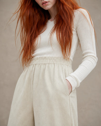 Close-up van de elastische taille en zijzak van een gebroken witte ingekorte wijde broek dames in tencel-linnenmix.