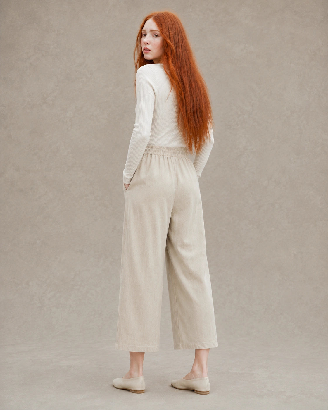 Achteraanzicht van model in een kaki ingekorte wijde broek dames in tencel-linnenmix met elastische taille.