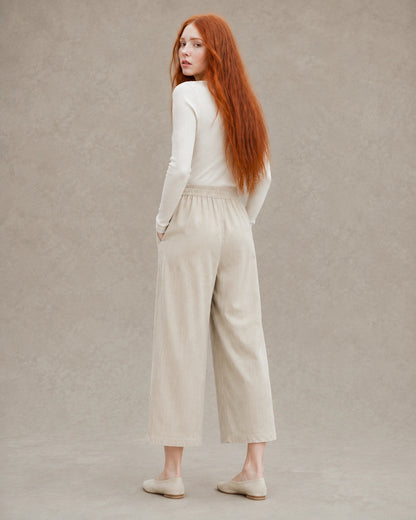 Achteraanzicht van model in een kaki ingekorte wijde broek dames in tencel-linnenmix met elastische taille.