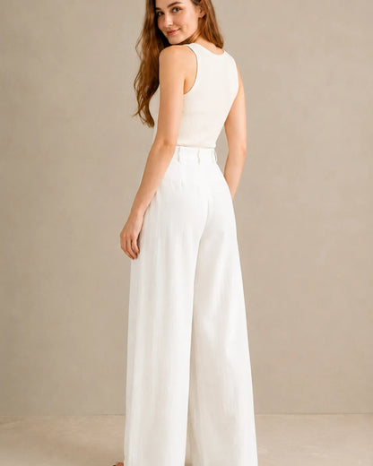 Three-quarter back view of model wearing white wide-leg trousers in a tencel-linen blend with a draped finish.