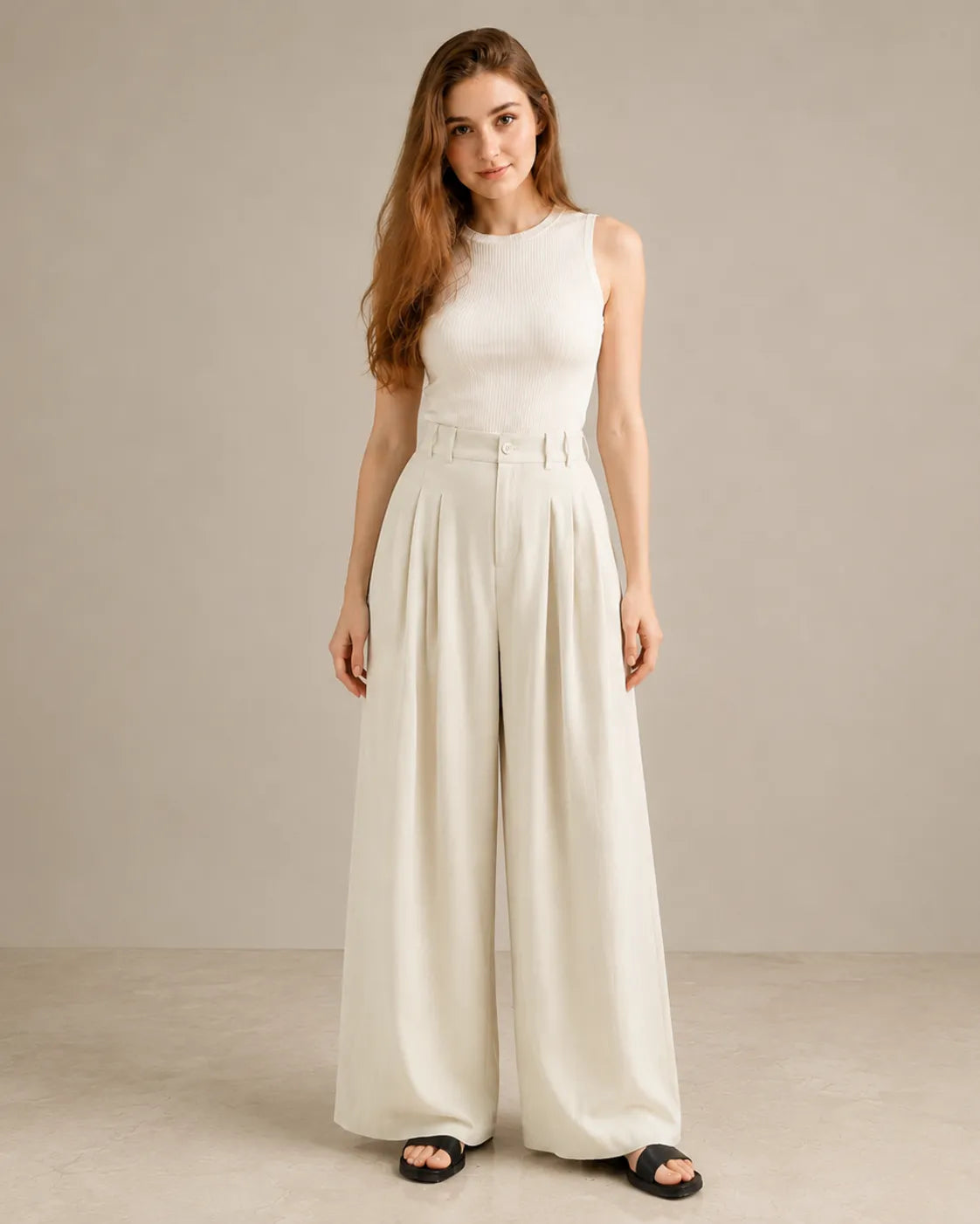 Close-up front view of model in white wide-leg trousers in a tencel-linen blend with a draped finish, styled with an ivory ribbed tank top.