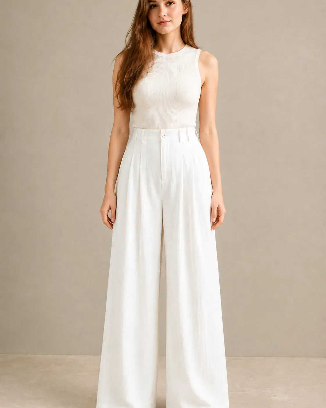 Model wearing white wide-leg trousers in a tencel-linen blend with a draped finish, front view, styled with an ivory ribbed tank top.