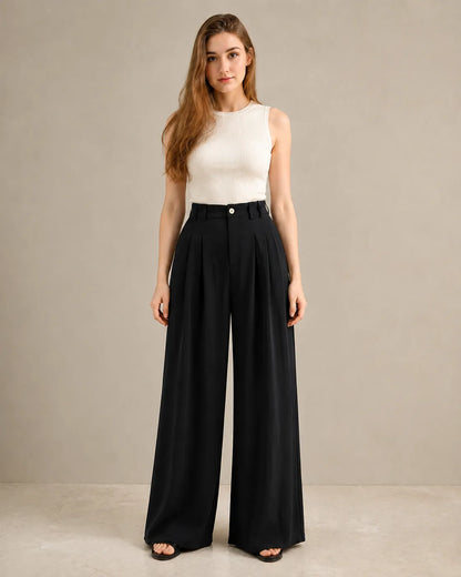 Model wearing black wide-leg trousers in a tencel-linen blend with a draped finish, front view, styled with an ivory ribbed tank top.
