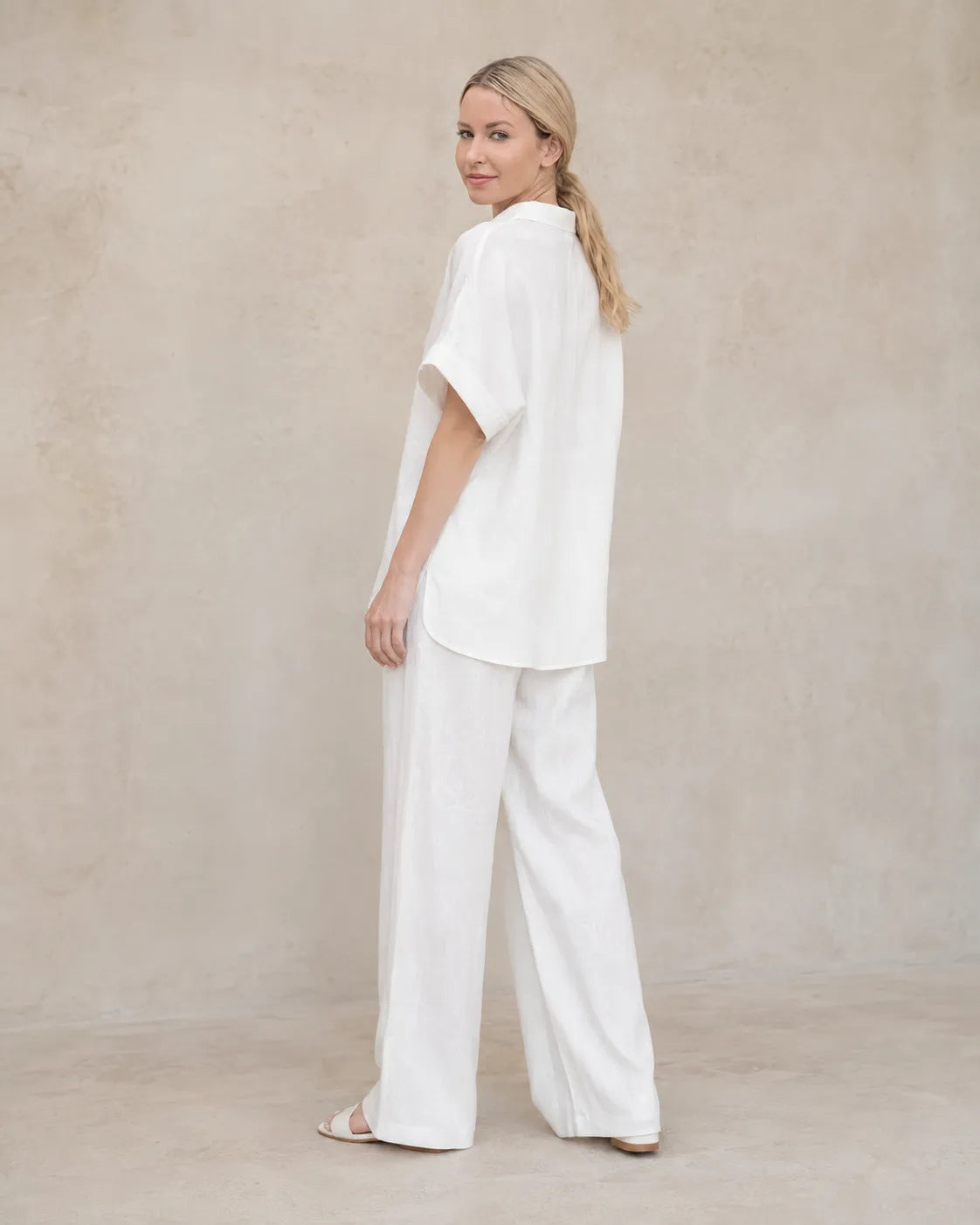 Achteraanzicht van een model in de witte co-ord set, met zicht op de manchet van de lange mouw.