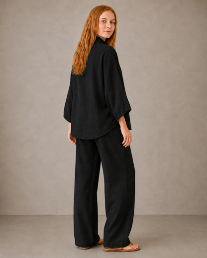 Back view of a model in the black cotton-linen co-ord set, showing the shirt falling over the trousers.