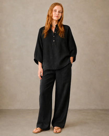 A model wears the black cotton-linen co-ord set, styled with a long-sleeve collared shirt and matching trousers.