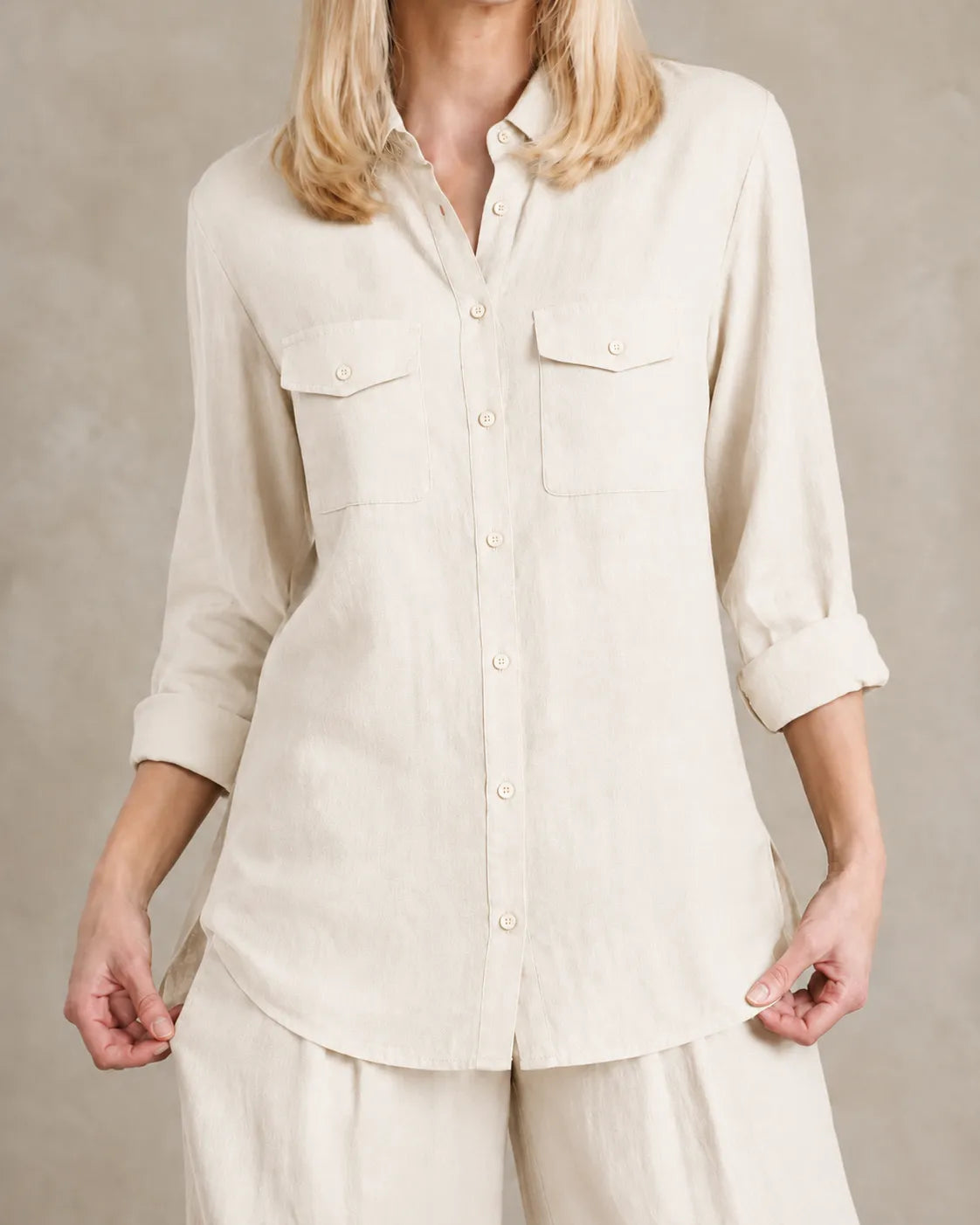 Close-up van de borstzakken en knoopsluiting van de beige-witte linnen co-ord set.