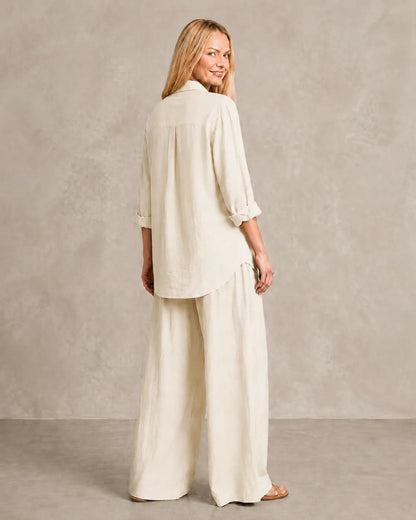 Achteraanzicht van de beige-witte linnen co-ord set, met de blouse losvallend over de wijde broek.