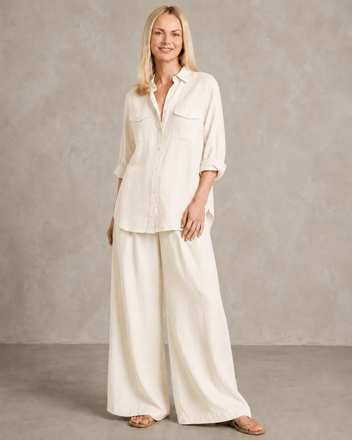 Een model draagt de linnen co-ord set in beige-wit, met een blouse en bijpassende wijde broek, in een ontspannen vooraanzicht.