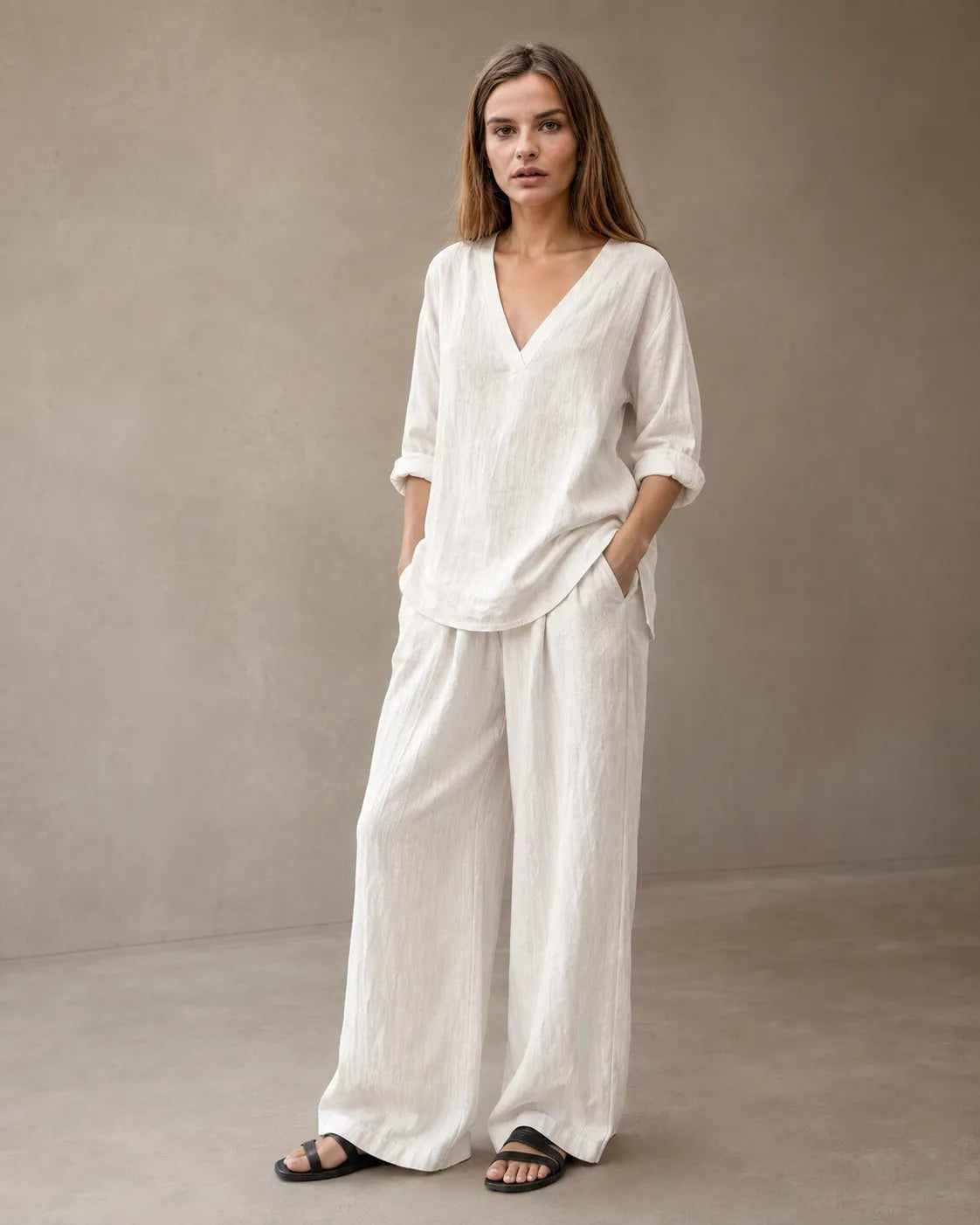 Een model draagt de linnenmix co-ord set met V-hals in gebroken wit, met een tuniektop met lange mouwen en een bijpassende geplooide wijde broek.