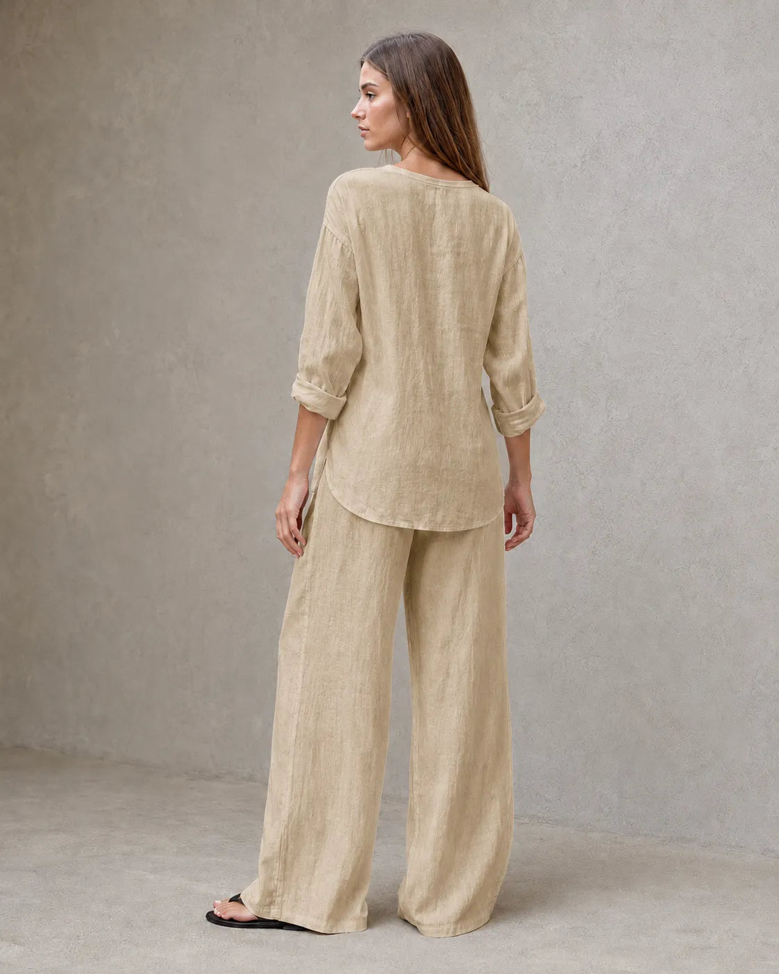 Achteraanzicht van een model in de kaki linnenmix co-ord set met V-hals, met de tuniektop vallend over de geplooide broek.