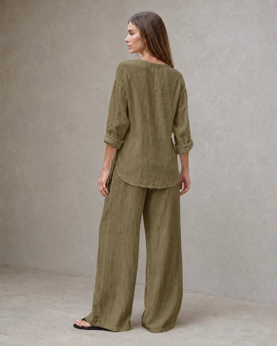 Achteraanzicht van een model in de olijfgroene linnenmix co-ord set met V-hals, met de tuniektop vallend over de geplooide broek.