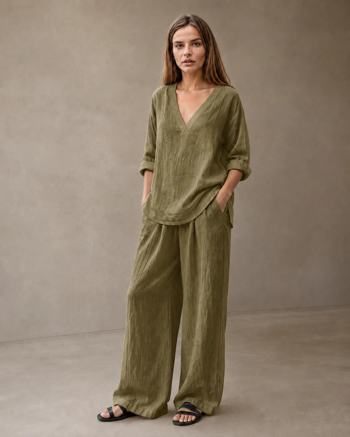Een model draagt de linnenmix co-ord set met V-hals in olijfgroen, met een tuniektop en een bijpassende geplooide wijde broek.