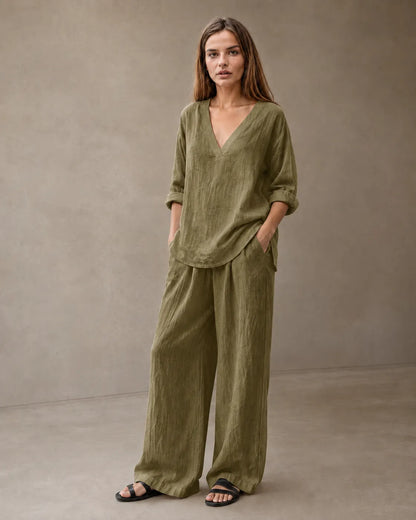 Een model draagt de linnenmix co-ord set met V-hals in olijfgroen, met een tuniektop en een bijpassende geplooide wijde broek.