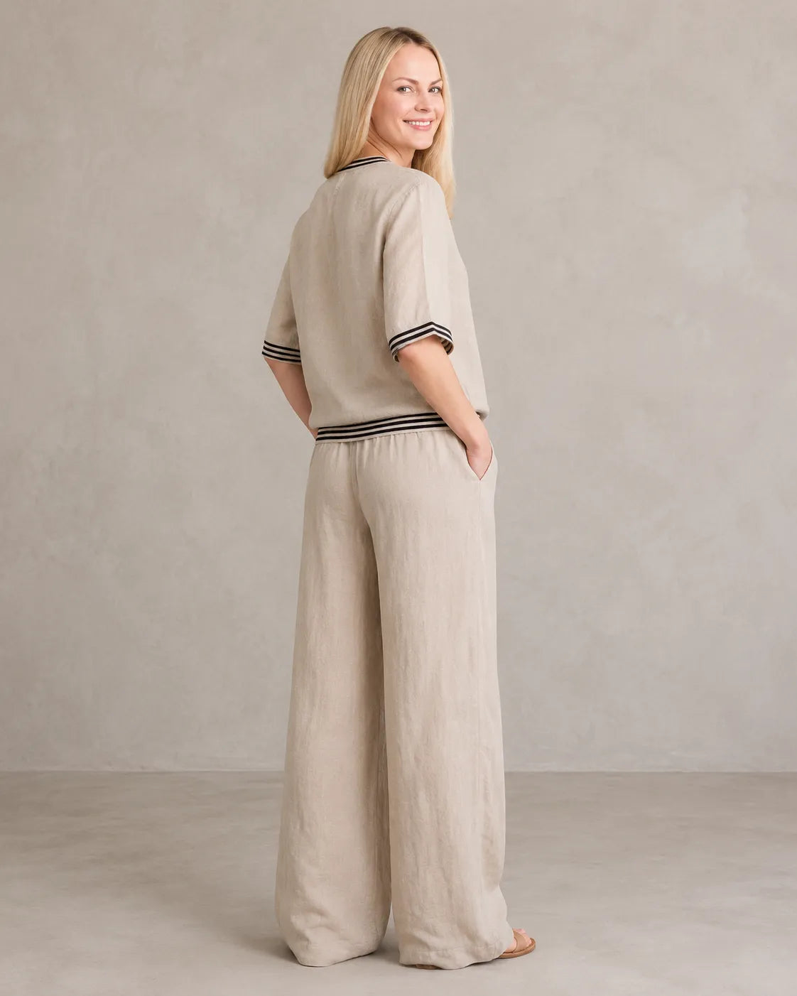 Achteraanzicht van een model in de kaki linnen co-ord set met V-hals, met de gestreepte taille en wijde broek.