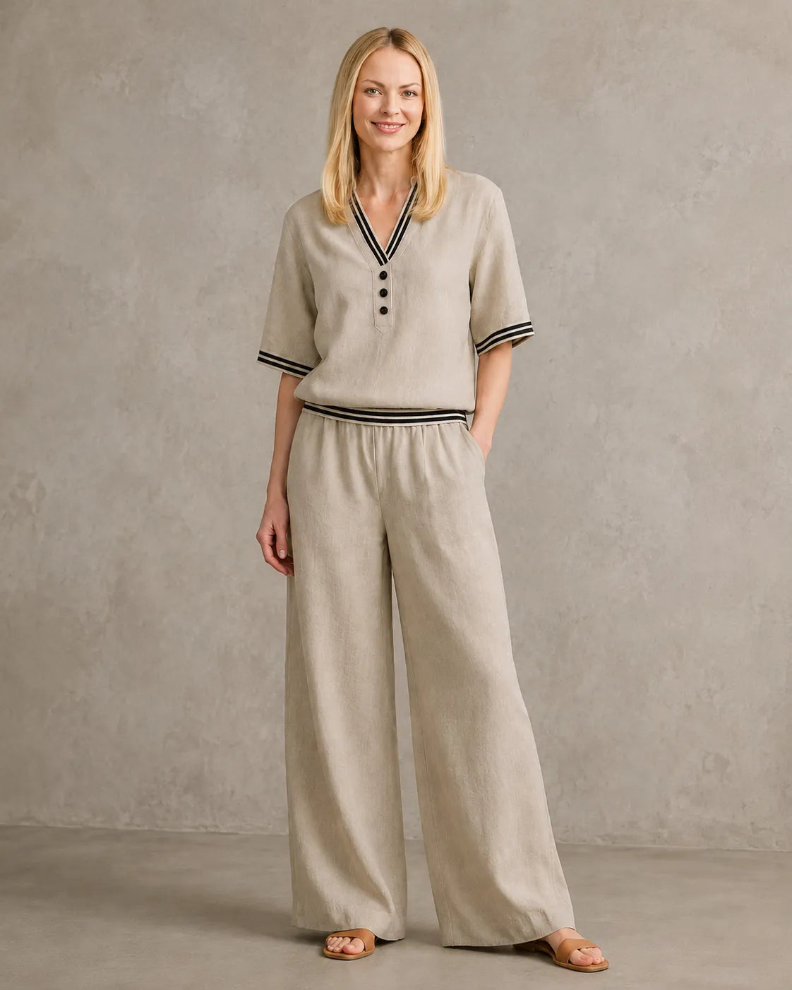 Een model draagt de linnen co-ord set met V-hals in kaki, met een top met gestreepte boorden en een bijpassende wijde broek.