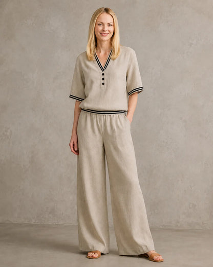 Een model draagt de linnen co-ord set met V-hals in kaki, met een top met gestreepte boorden en een bijpassende wijde broek.