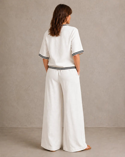 Achteraanzicht van een model in de melkwitte linnen co-ord set met V-hals, met de gestreepte taille en wijde broek.
