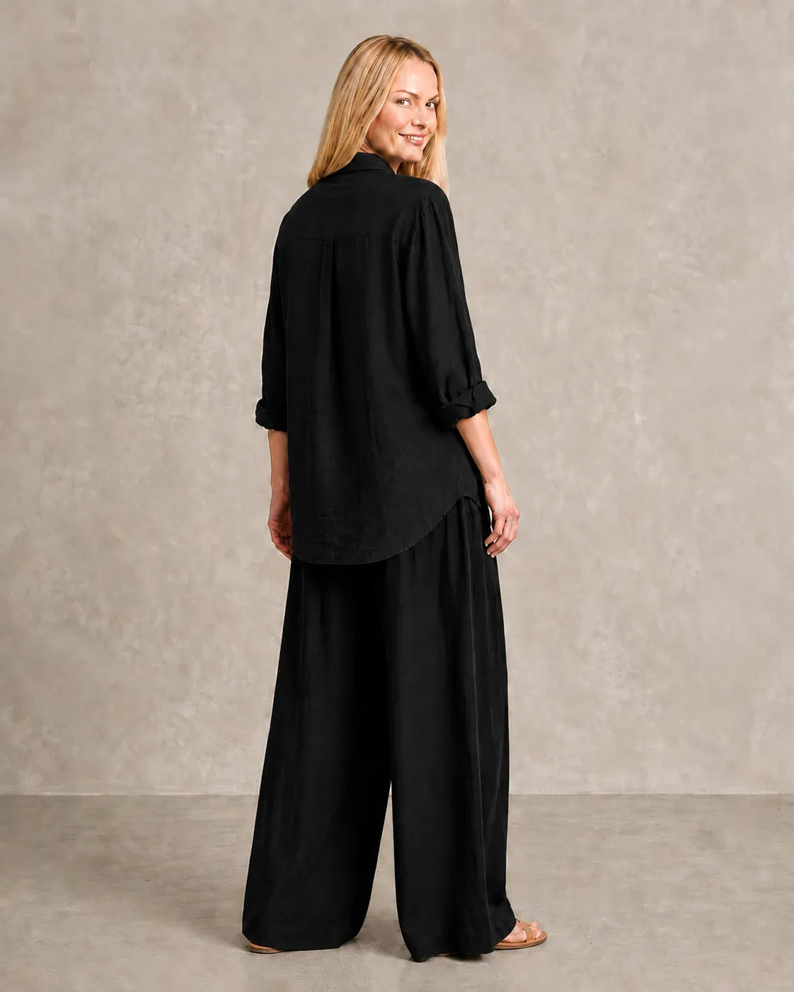 Achteraanzicht van de zwarte linnen co-ord set, met de blouse vallend over de wijde broek.