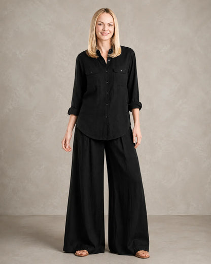 Een dichterbij vooraanzicht van een model in de zwarte linnen co-ord set, met de borstzakken en knoopsluiting van de blouse.