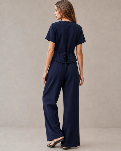 Achteraanzicht van een model in de marineblauwe tencel-linnen co-ord set, met de strikceintuur aan de achterkant van de top en de wijde broek.