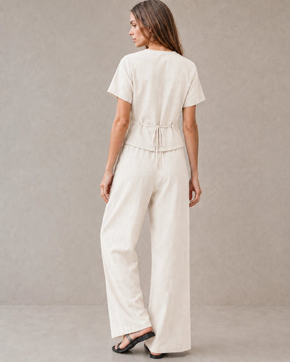 Achteraanzicht van een model in de off-white tencel-linnen co-ord set, met de strikceintuur aan de achterkant van de top en de wijde broek.