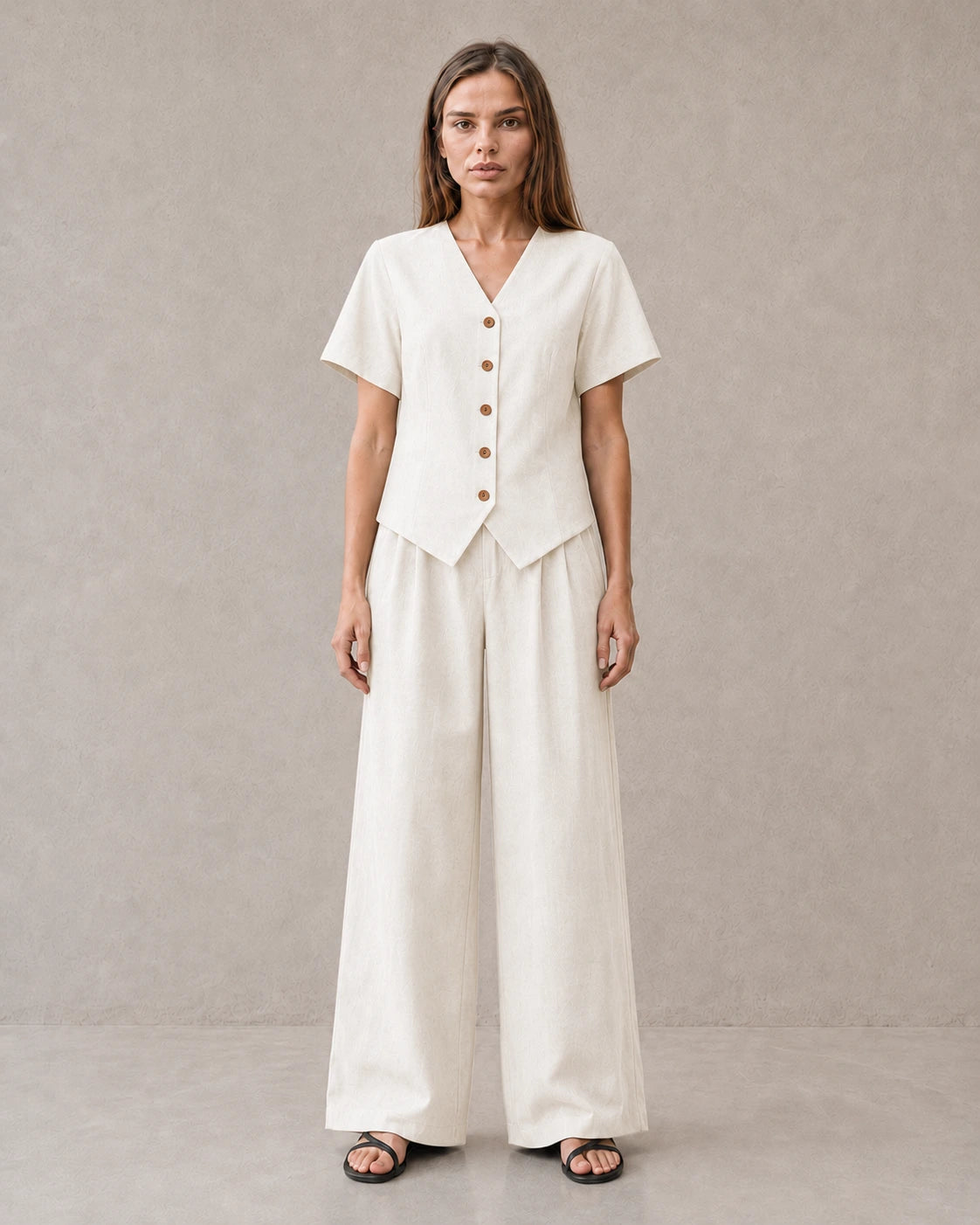 Een dichterbij vooraanzicht van een model in de off-white tencel-linnen co-ord set, met de V-hals en knoopsluiting van de top.