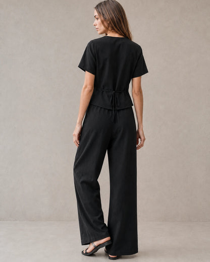 Achteraanzicht van een model in de zwarte tencel-linnen co-ord set, met de strikceintuur aan de achterkant van de top en de wijde broek.
