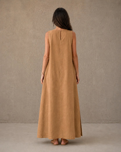 Achteraanzicht van een mouwloze linnen A-lijn jurk in camel met knoopsluiting bij de hals, gedragen door een model.