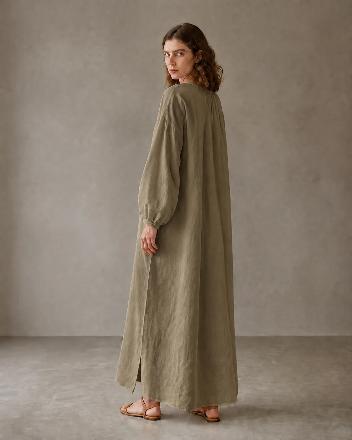 Back view of a khaki cotton-linen dress with long sleeves and a side hem slit, shown on a model.