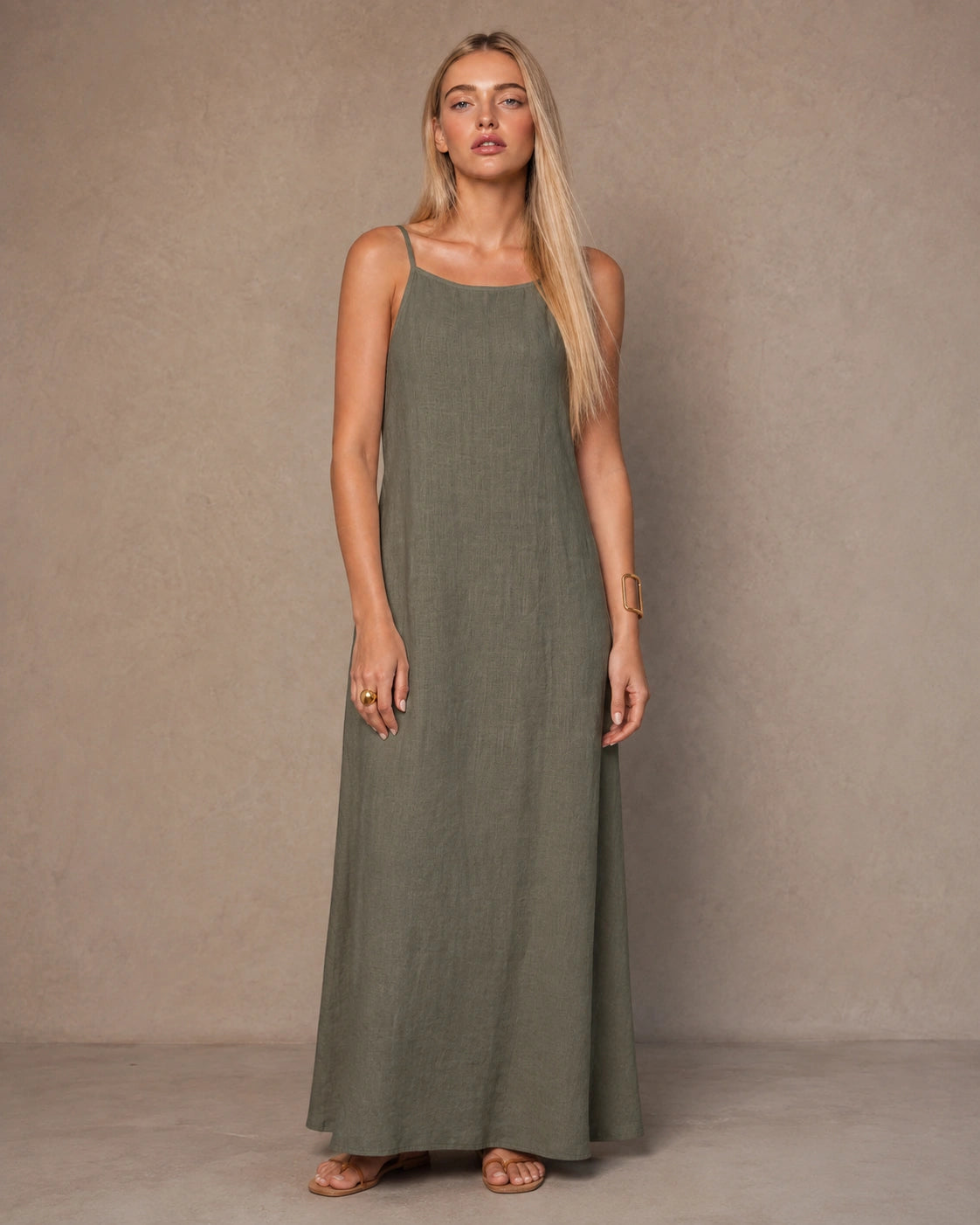 Woman wearing an army green cotton-linen halter dress with thin adjustable straps and a flowing A-line skirt, shown from the front.