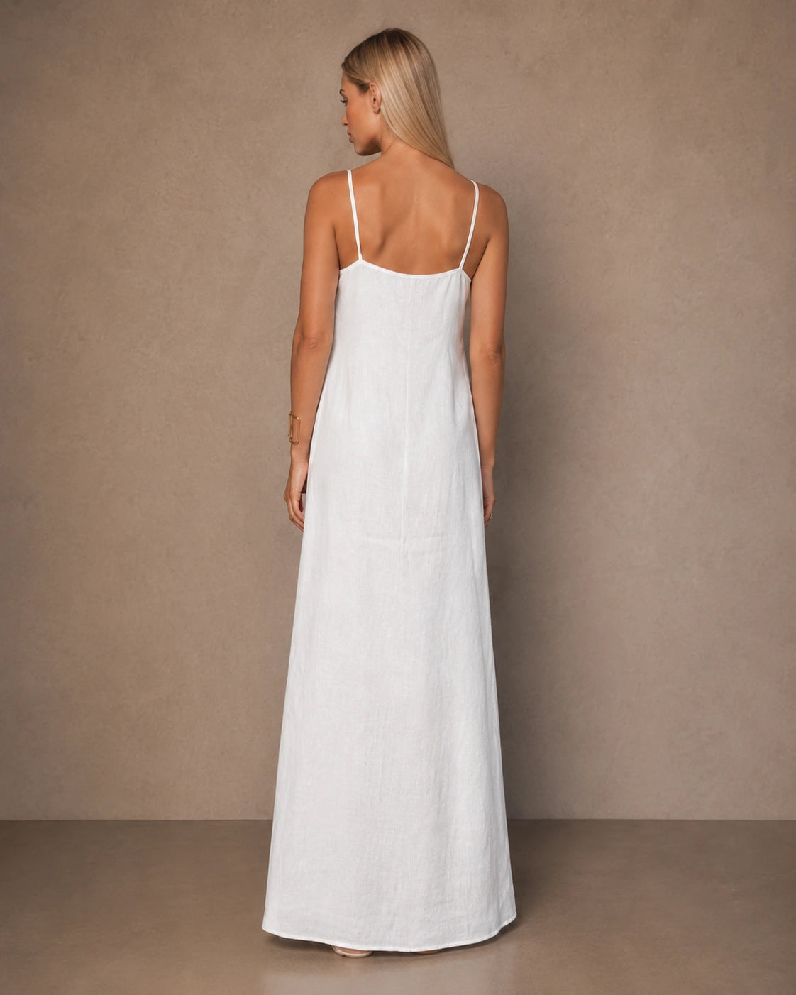Back view of a white cotton-linen halter dress with thin adjustable straps, shown on a model.