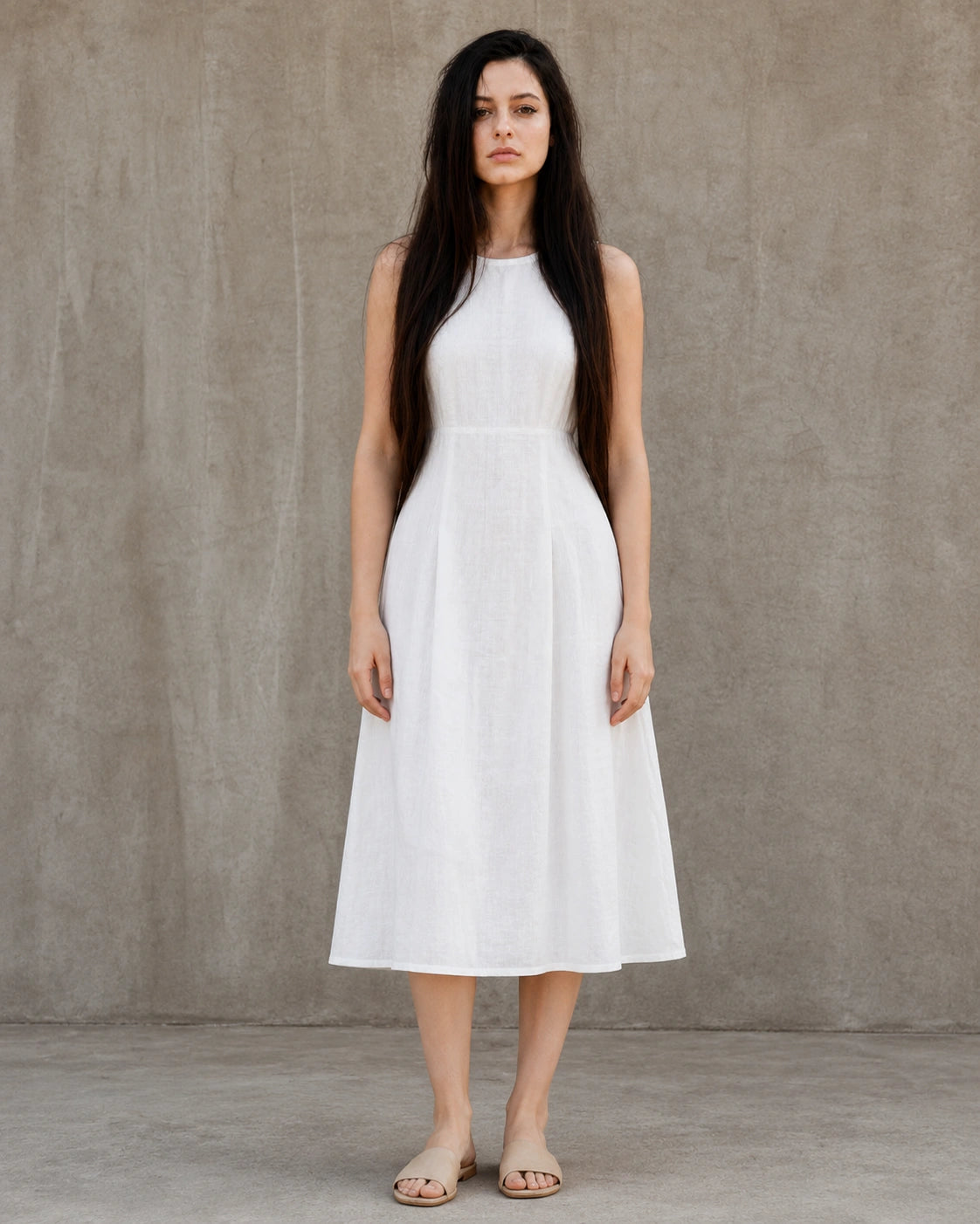 Woman wearing a white linen-cotton midi dress with a round neckline, fitted waist seam and A-line skirt, shown from the front.