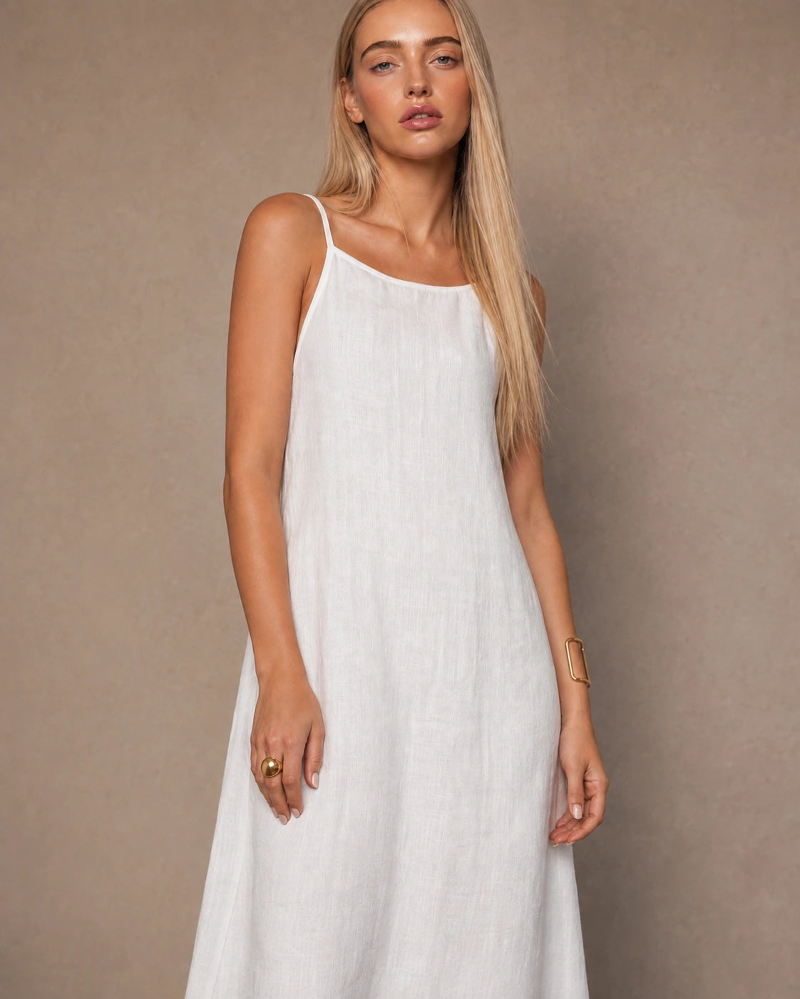 Close-up of a woman wearing a white cotton-linen halter dress with thin adjustable straps and a square neckline.