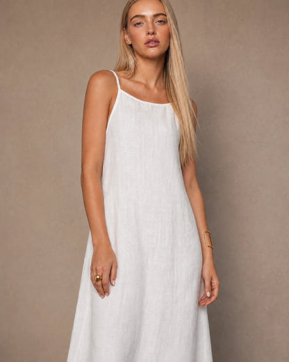 Close-up of a woman wearing a white cotton-linen halter dress with thin adjustable straps and a square neckline.