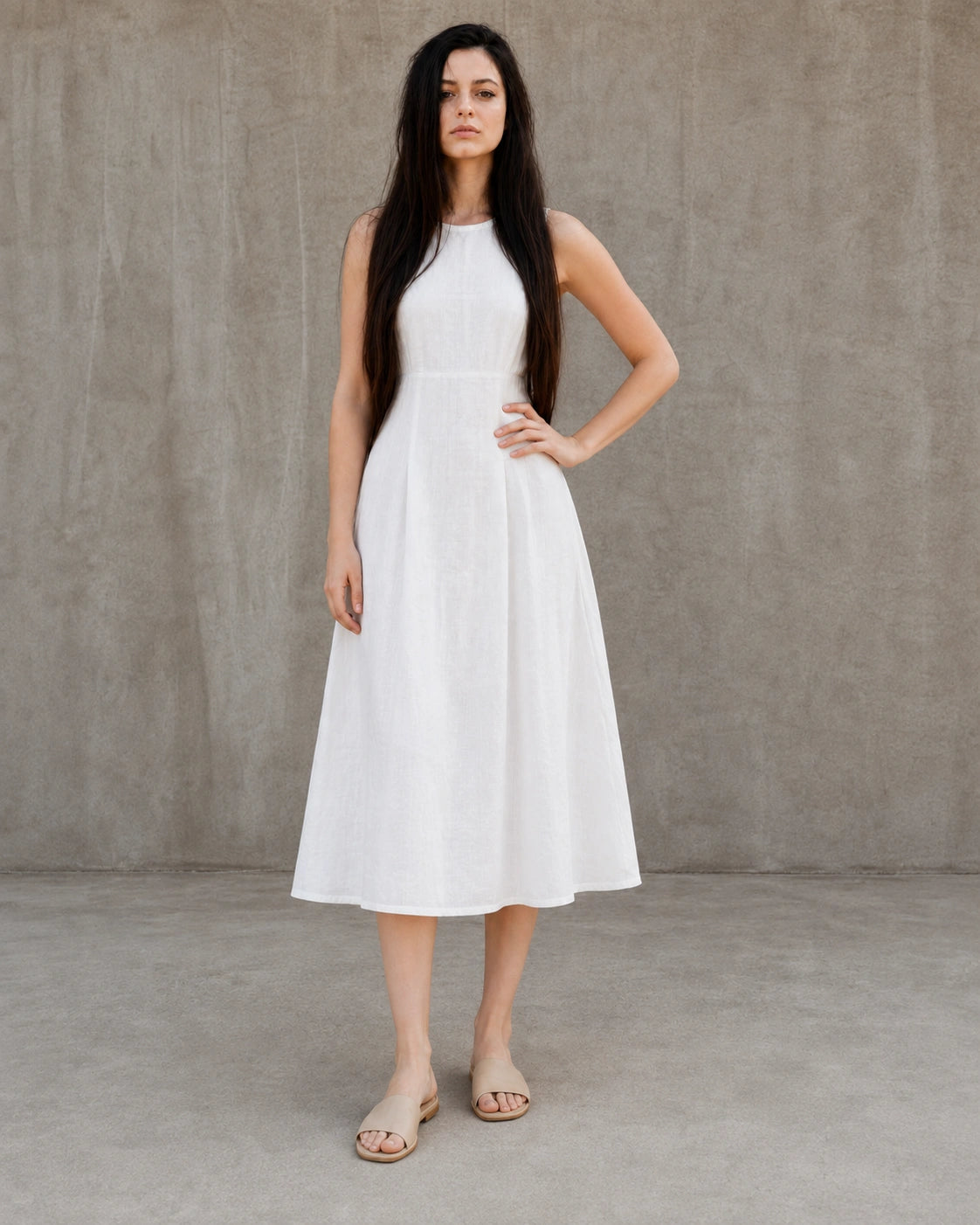 Woman wearing a white linen-cotton midi dress with a fitted waist seam, hand on hip, shown from the front.