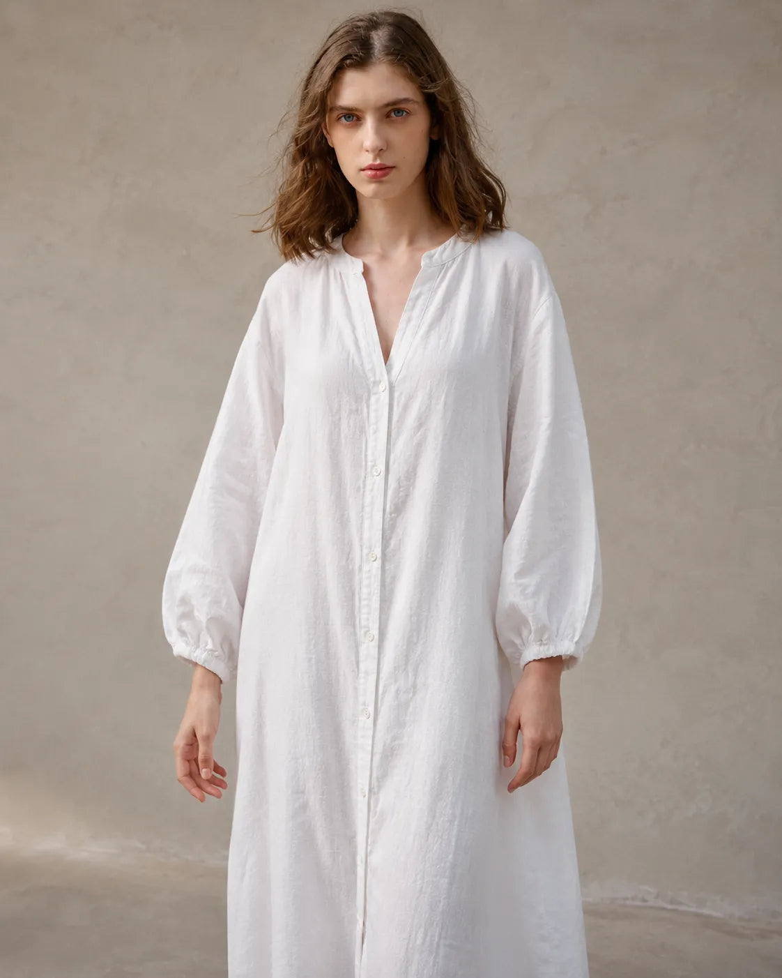Close-up of a woman wearing a white cotton-linen dress, showing the long balloon sleeves with elasticated cuffs.