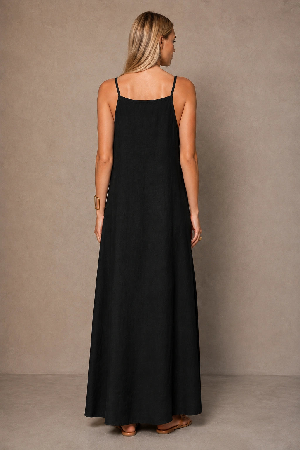 Back view of a black cotton-linen halter dress with thin adjustable straps, shown on a model.