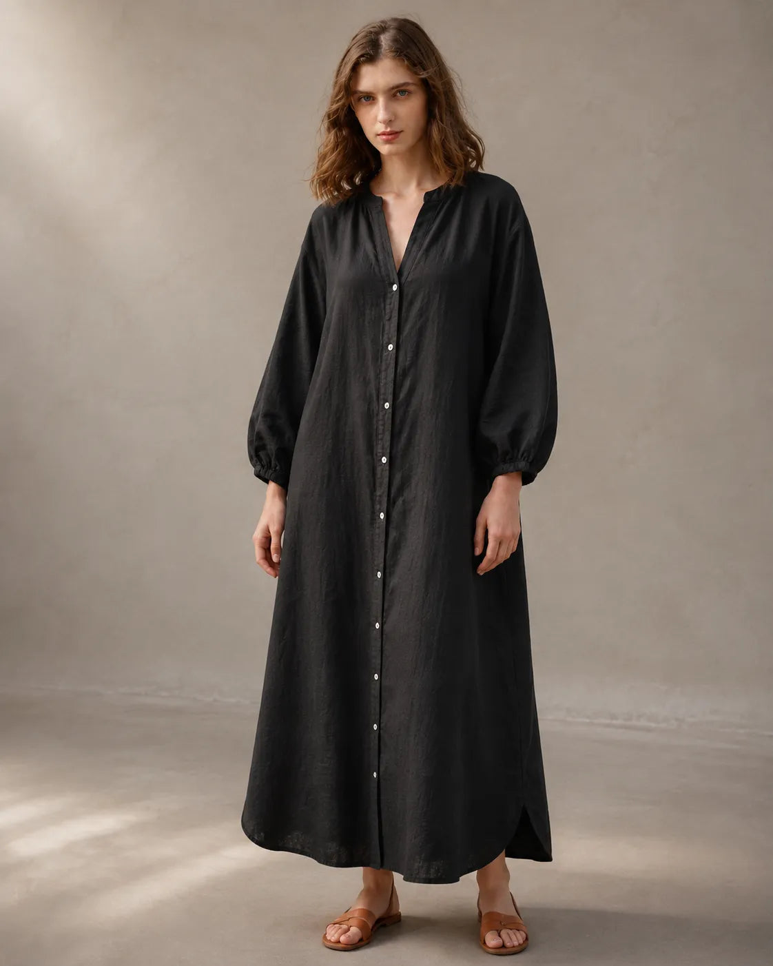 Close-up of a woman wearing a black cotton-linen dress, showing the long balloon sleeves with elasticated cuffs.