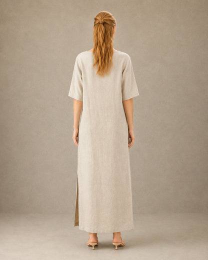 Achteraanzicht van een linnen-tencel jurk in hennep-beige met mouwen tot de elleboog, gedragen door een model.