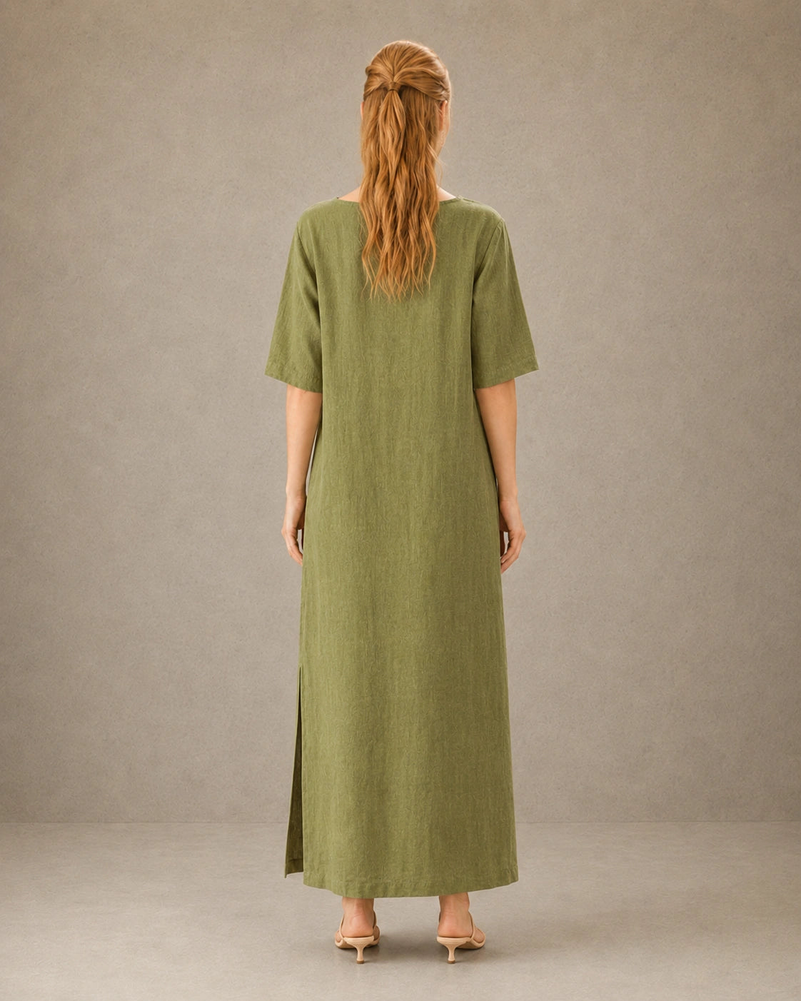 Achteraanzicht van een linnen-tencel jurk in mosterdgroen met mouwen tot de elleboog, gedragen door een model.