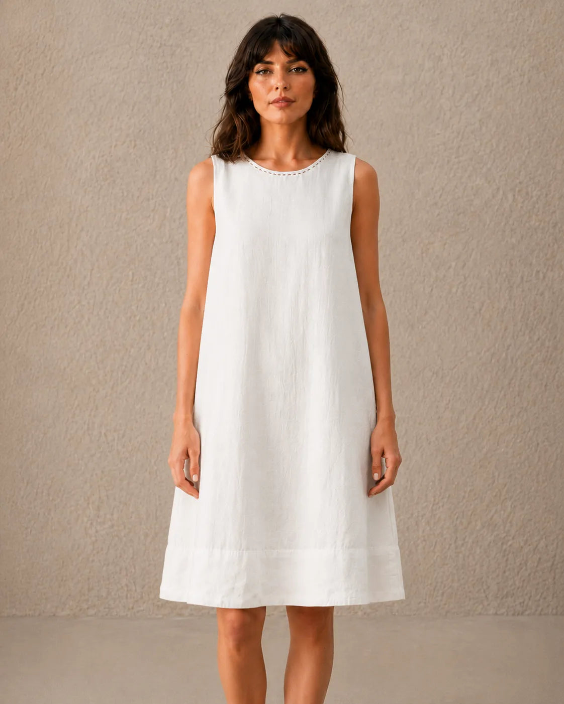 Close-up van een vrouw in een linnen-tencel A-lijn jurk in wit, met zicht op de hals met kraalborduursel.