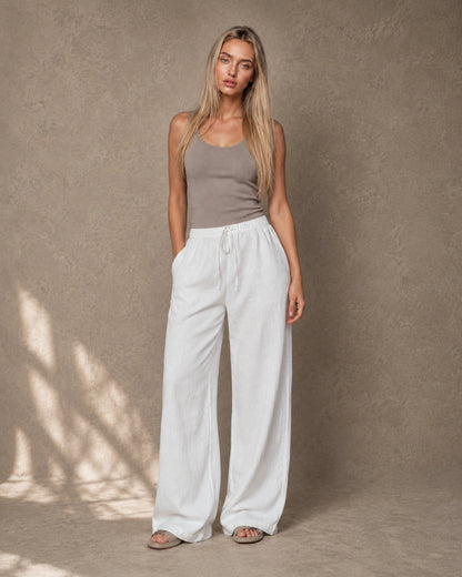 Model draagt een witte hoge taille pantalon dames in katoen-linnen-viscosemix met elastische trekkoordtaille, gestyled met een taupe topje, vooraanzicht.