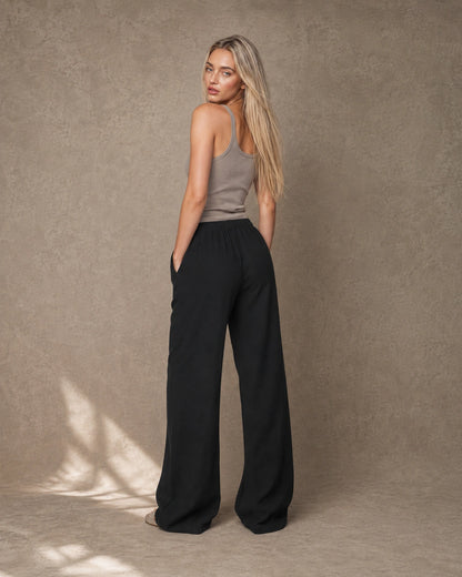 Achteraanzicht van model in een zwarte hoge taille pantalon dames in katoen-linnen-viscosemix met elastische taille.