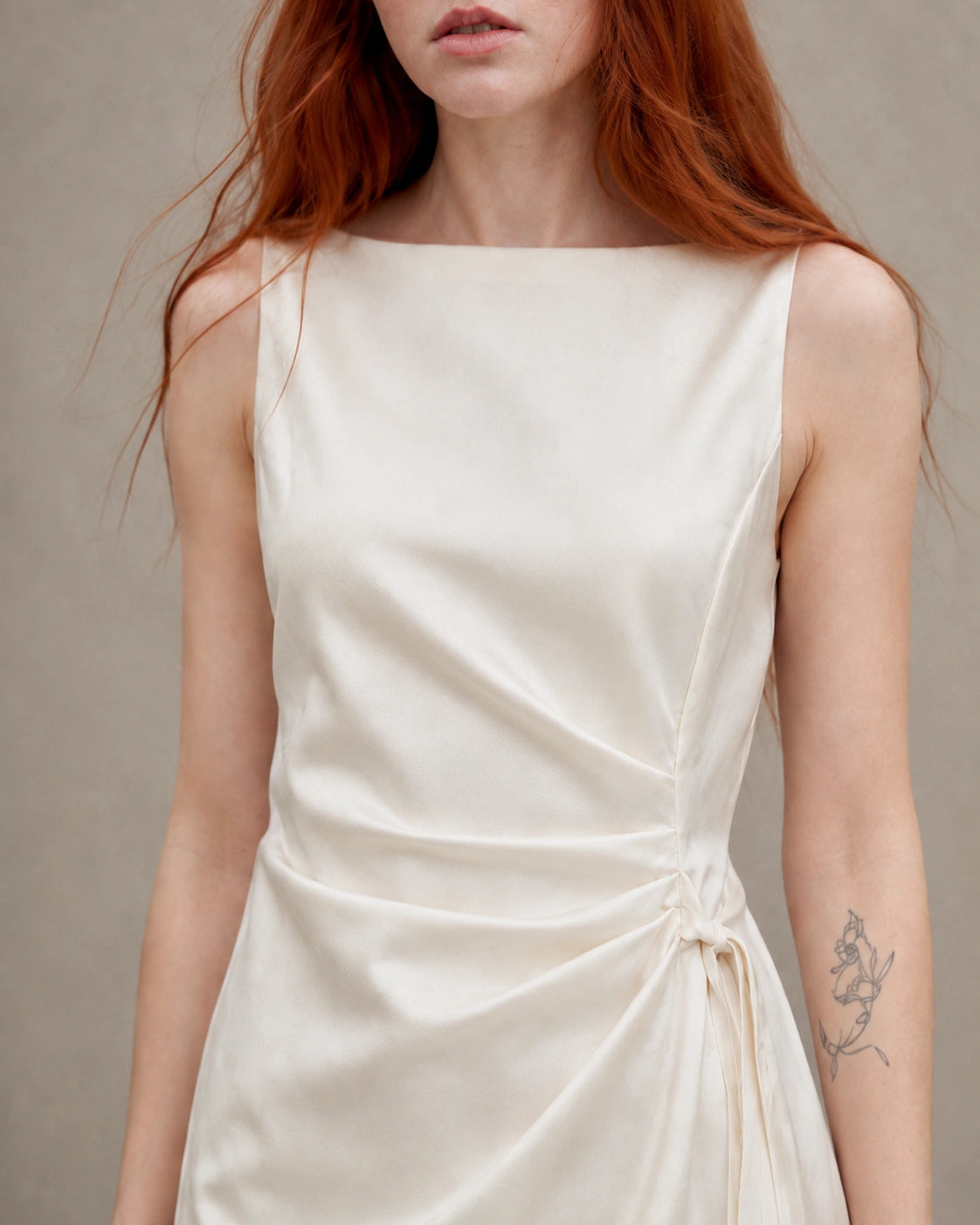 Close-up of the fabric knot tie at the waist of an apricot tencel-linen dress, shown on a model.