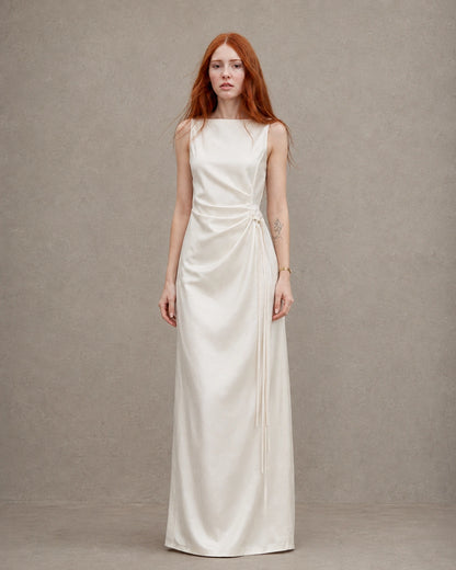 Woman wearing an apricot tencel-linen fitted dress with a high waist seam and side tie detail, shown from the front.